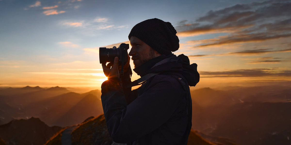 Photographer capturing a mountain sunset with a camera from a high alpine viewpoint
