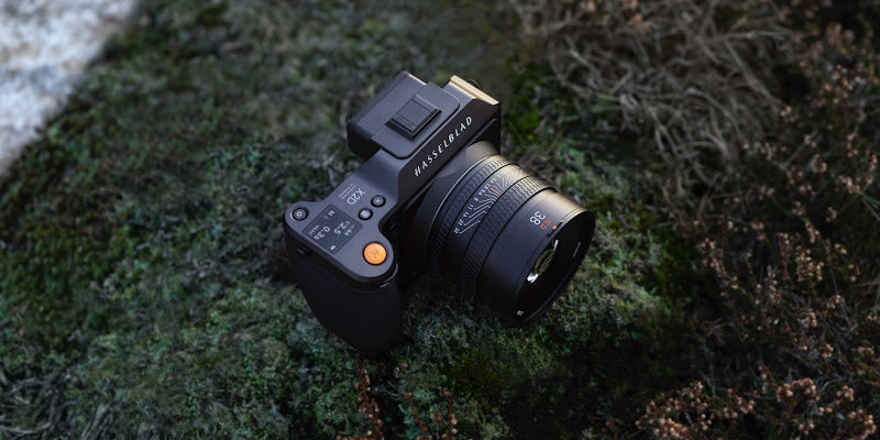 Hasselblad X2D 100C with an XCD 38V lens resting on a moss-covered rock outdoors